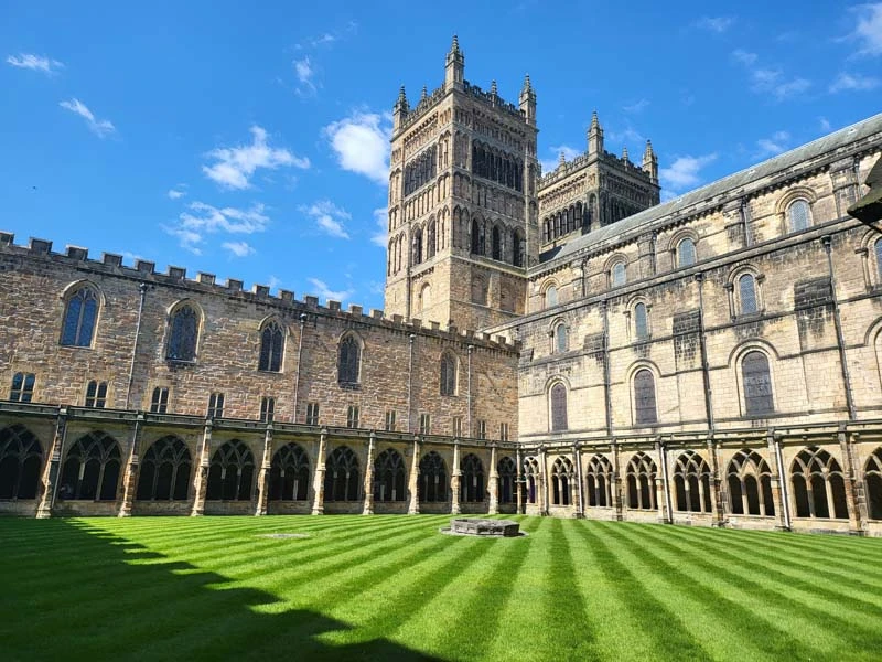 Exterior photo of Durham Cathedral. Green striped lawn in front of Durham Cathedral towers. Just one of many things to do in Durham for couples