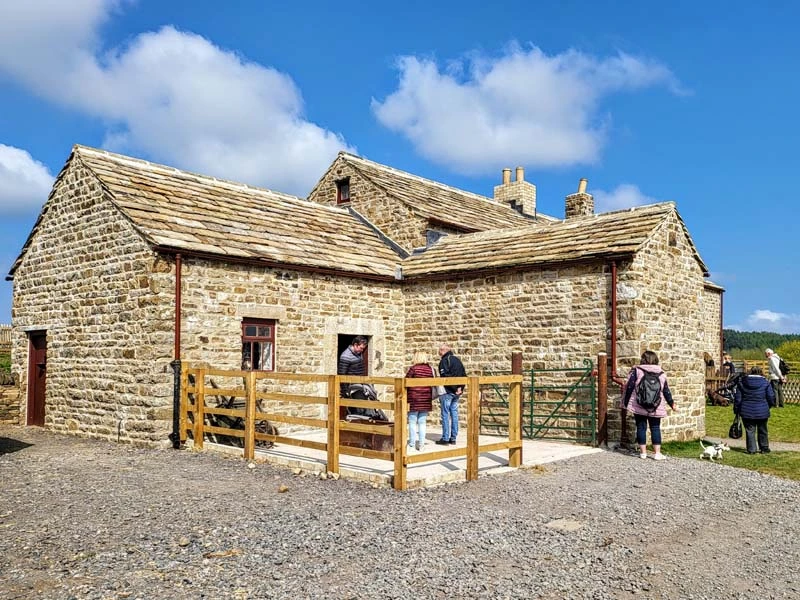 Exterior photo of Spain's Field Farm building. The house is centre of image with gravel path in lower half and blue sky in top half of image. 