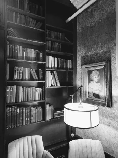 Black and white image of bookshelf and framed portrait on right side wall. Just one of many things to do in Durham for couples