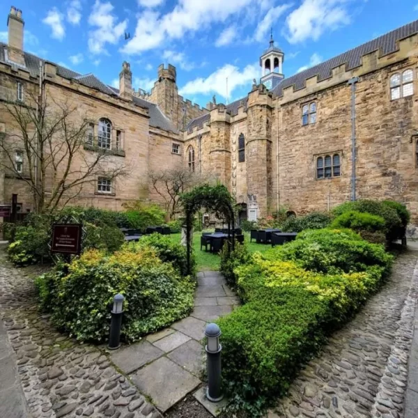 Lumley Castle courtyard with green hedges to the left and right side. Blue sky above castle walls. Just one of many things to do in Durham for couples