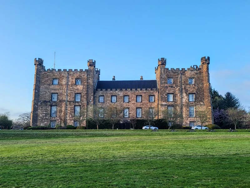 Wide angle of Lumley Castle. Green grass in the foreground and castle in the middle of the image. Just one of many things to do in Durham for couples