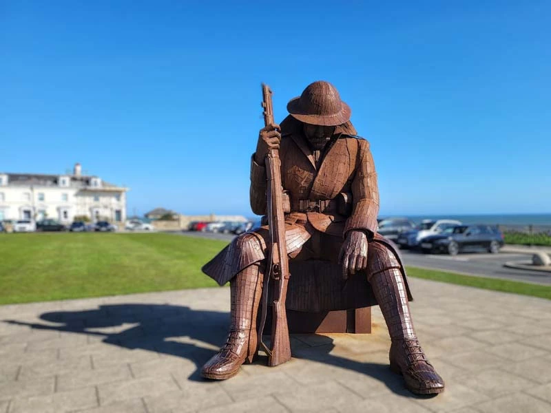 Sculpture of "Tommy", rusted red colour, and set against a blue sky background