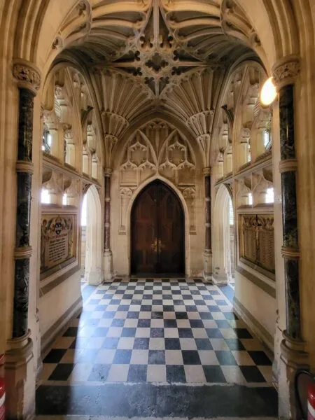 Interior photo of chapel. Black and white checked tiles. Ornately carved chapel. 