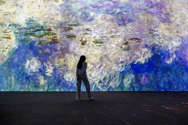 Person standing in front of large screen of Monet artwork